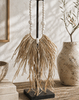 Decorative item with white beads and dried grasses on a wooden surface