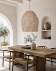 Dining area with wooden table, chairs, and a woven pendant light.