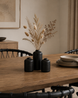 Dining room with a wooden table, black vases, and decorative items.