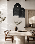 Modern dining room with a concrete table, wooden chairs, and black pendant lights.