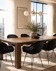Modern dining room with large wooden table and black chairs, featuring a city skyline view.