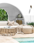 Outdoor seating area with a sofa, coffee table, and decorative items by a pool.