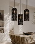 Three black woven pendant lights hanging in a modern interior setting with a stone table and shelves.