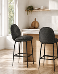 Two dark gray bar stools in a kitchen setting with natural light.