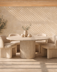 Alama dining table in dune hydro dipped finish with round top and fluted pedestal base styled in a sunlit textured room with soft neutral seating.