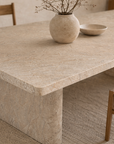 Amani dining table in dune hydro dipped finish with rectangular top and sculptural base styled in a warm minimal dining room with natural wood chairs.