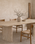 Amani dining table in dune hydro dipped finish with rectangular top and sculptural base styled in a warm minimal dining room with natural wood chairs.