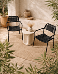Amila black armchairs with woven rope seats styled around a stone side table in a calm mediterranean inspired courtyard setting
