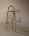 A minimalist solid ashwood bar stool with a curved backrest and natural finish, designed for modern kitchen and bar spaces