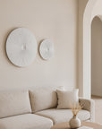 KULALA Living Aura Wall Art featuring two white textured disc sculptures above a soft neutral sofa in a minimalist lounge interior