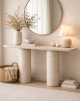 Ayanda console in dune hydro dipped finish with rounded top and cylindrical bases styled in a soft neutral entryway with mirror and warm lighting.