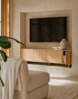 Bajo Sideboard crafted from natural oak styled in a modern living room with neutral tones, featuring a floating design beneath a wall-mounted TV and ceramic vase