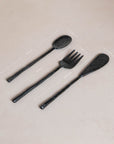 A set of three handcrafted black cutlery pieces from KULALA Living, including a spoon, fork, and knife, featuring a hand-forged finish with textured handles for a refined yet rustic dining aesthetic