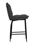 A black metal bar stool with a cushioned seat and backrest upholstered in dark linen fabric. Featuring a sleek yet relaxed design, this stool blends comfort with modern sophistication, ideal for contemporary kitchens or bar spaces