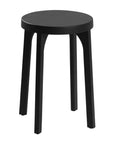 A sleek black oak round stool featuring a minimalist design with subtly curved legs. Crafted from solid oak with a matte black finish, this versatile piece functions as a stool or side table, adding a modern touch to any space