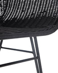 Black rattan dining chair with curved back and slim metal legs, perfect for modern and stylish dining settings