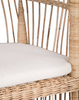 A beautifully crafted blonde rattan armchair with an open-weave design and a white cushioned seat, perfect for adding a relaxed coastal touch to any space.