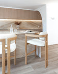Curved-back boucle and rubberwood bar stools at a marble kitchen island with timber cabinetry and soft, natural tones in a modern Australian home.