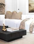A beautifully styled modern living room featuring KULALA Living’s brass candlestick holders on a black timber coffee table. Neutral tones, textured cushions, and a soft woven throw create a warm and inviting aesthetic, complemented by curated books and a sleek black candle for a touch of sophistication