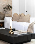 A beautifully styled living room showcasing KULALA Living’s brass candlestick holders on a black timber coffee table. The neutral palette, textured cushions, and soft woven throw create a serene and sophisticated atmosphere, complemented by curated books and a sleek black candle