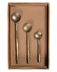A set of three handcrafted brass spoons from KULALA Living, featuring an artisanal hammered finish and elegantly tapered handles, perfect for serving and stirring with style