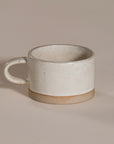 A beautifully handcrafted ceramic coffee mug and matching cup, featuring a minimalist stoneware design with a natural speckled glaze and raw clay base. Perfect for enjoying your morning coffee or tea in a timeless, artisanal style