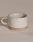 A beautifully handcrafted ceramic coffee mug and matching cup, featuring a minimalist stoneware design with a natural speckled glaze and raw clay base. Perfect for enjoying your morning coffee or tea in a timeless, artisanal style