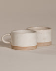 A beautifully handcrafted ceramic coffee mug and matching cup, featuring a minimalist stoneware design with a natural speckled glaze and raw clay base. Perfect for enjoying your morning coffee or tea in a timeless, artisanal style