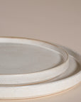 A set of handcrafted ceramic dinner plates in a soft speckled stoneware finish, featuring a minimalist design with a slightly raised rim. Perfect for modern, organic-style dining