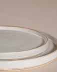 A set of handcrafted ceramic dinner plates in a soft speckled stoneware finish, featuring a minimalist design with a slightly raised rim. Perfect for modern, organic-style dining