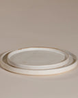 A set of handcrafted ceramic dinner plates in a soft speckled stoneware finish, featuring a minimalist design with a slightly raised rim. Perfect for modern, organic-style dining
