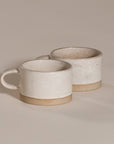 A beautifully handcrafted ceramic coffee mug and matching cup, featuring a minimalist stoneware design with a natural speckled glaze and raw clay base. Perfect for enjoying your morning coffee or tea in a timeless, artisanal style