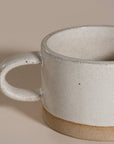 A beautifully handcrafted ceramic coffee mug and matching cup, featuring a minimalist stoneware design with a natural speckled glaze and raw clay base. Perfect for enjoying your morning coffee or tea in a timeless, artisanal style