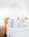 Natural white boho bedroom with a minimalist setting and teak side table.