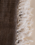 Soft cotton throw blanket in beige and brown with fringe detailing, adding a touch of natural texture to any living space