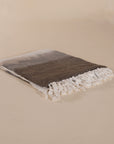Soft cotton throw blanket in beige and brown with fringe detailing, adding a touch of natural texture to any living space