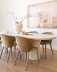 Dining Table in creamy textured finish styled with sculptural decor and six upholstered chairs in a soft neutral dining setting with timber floors