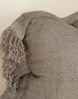A beautifully textured handwoven linen cushion cover in a soft natural hue, featuring delicate fringe details for a relaxed, organic look. Ideal for layering on sofas or beds