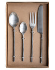A set of four handcrafted stainless steel cutlery pieces with hand-forged handles, elegantly presented in a minimalist kraft gift box. Includes a dinner knife, fork, tablespoon, and teaspoon for a refined dining