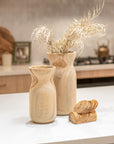Handcrafted teak vases and coasters styled on a modern kitchen bench, showcasing natural timber grain and organic shapes.