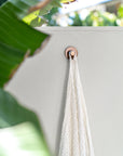 Ivory handloom linen bath towel hanging on an outdoor wall beside tropical foliage and timber decking, capturing a relaxed resort-style atmosphere by the pool.