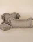 A handwoven throw in a warm, neutral tone, neatly folded with fringed edges. The textured fabric adds a natural, rustic charm, perfect for layering in any cozy living space