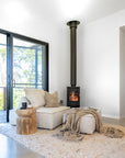 Cosy living room with the Jimmy Sofa in natural upholstery, paired with a sculptural wooden side table and fireplace, styled for relaxed comfort and warmth