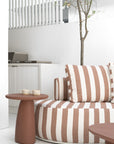 Laguna sofa in cinnabar clay stripe paired with Lantara side table creating a warm relaxed outdoor setting with soft earthy tones.
