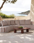 Laguna modular sofa in cinnabar stripe fabric styled outdoors with a lantara coffee table overlooking a coastal view.