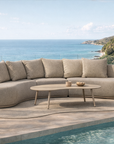 Laguna modular sofa in oat drift fabric paired with Solara coffee table styled beside a pool overlooking a coastal landscape.