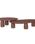 Lantara coffee table cluster in cinnabar clay finish with elongated oval top and three rounded sculptural legs.