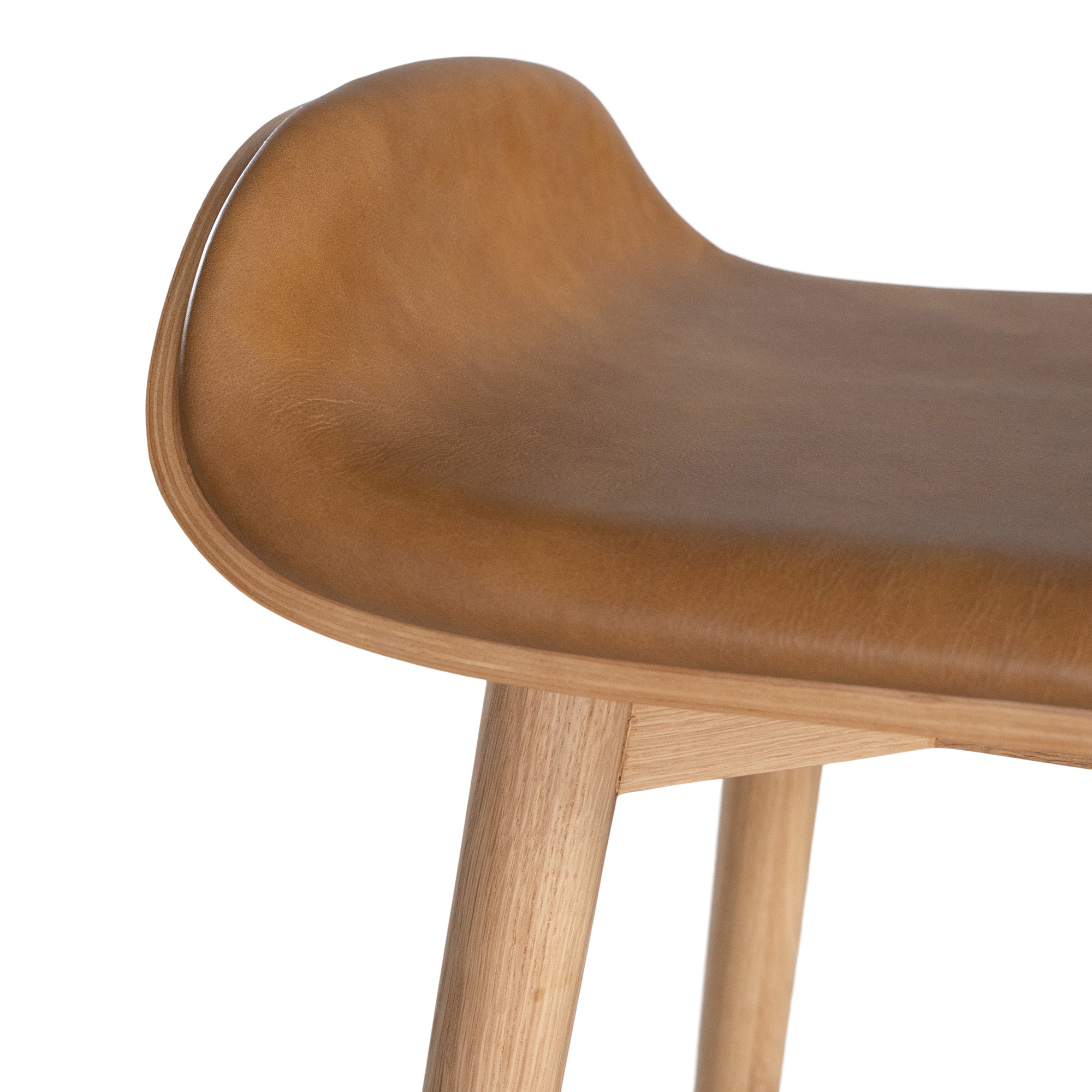 A stylish bar stool featuring a smooth tan leather seat and a sturdy natural oak frame. Designed with comfort and durability in mind, this contemporary stool is perfect for modern kitchens and dining spaces.