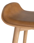 A stylish bar stool featuring a smooth tan leather seat and a sturdy natural oak frame. Designed with comfort and durability in mind, this contemporary stool is perfect for modern kitchens and dining spaces.
