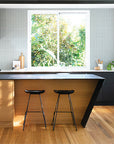 modern organic australian kitchen with two black barstools at a timber island and soft neutral styling